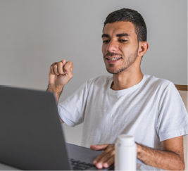 Young man sits at laptop, communicating through sign language