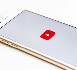 A smartphone laying on a bright white surface with a red play button visible onscreen