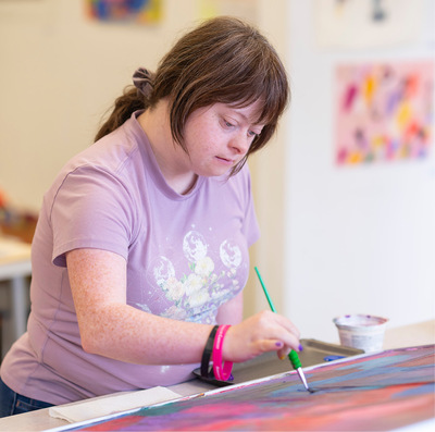 Young woman painting in art session.