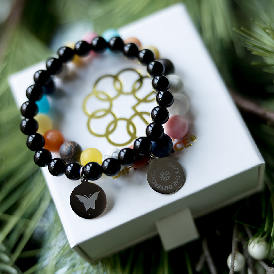 Two bracelets - one with black beads and the other multi-colored beads on top of a gift box